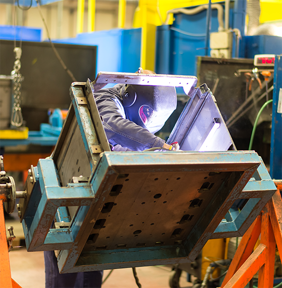 Operator welding a metal component for commercial vehicles